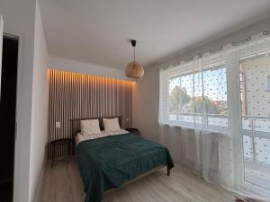 a bedroom with a bed and a large window at Latarnik in Karwia