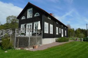 een zwart-wit huis met een hek eromheen bij Björnhofvda Gård in Björnhuvud