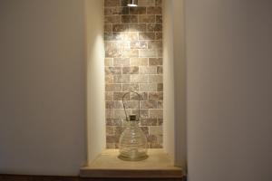 un vase en verre assis sur une étagère à côté d'un mur de briques dans l'établissement L'Ecrin du Val de Louyre, à Lentignac 9 autres photos