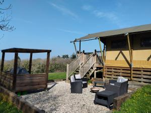 a house with a porch and a staircase and chairs at Beara Lodge Glamping in Beaworthy