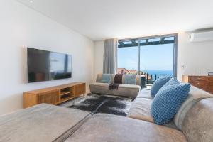 a living room with a couch and a flat screen tv at Sapphire Sands by Atlantic Holiday in Estreito da Calheta