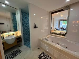 北芭堤雅Beachfront Luxe with Pool Access and Terrace的带浴缸、水槽和镜子的浴室