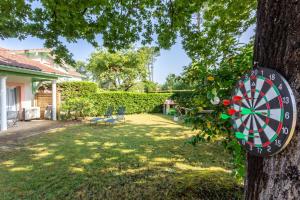 a dart board hanging on a tree in a yard at Proche lac : Maison avec beau jardin in Biscarrosse +6 photos