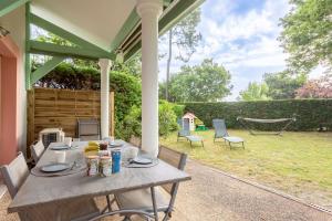 a table on a patio with a hammock in a yard at Proche lac : Maison avec beau jardin in Biscarrosse