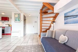 a living room with a couch and a staircase at Proche lac : Maison avec beau jardin in Biscarrosse