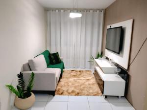 a living room with a couch and a tv at Refúgio do Aconchego Apto no primeiro andar P 4 pessoas in Caruaru