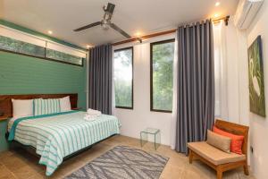 a bedroom with a bed and a chair and windows at Casa de Agua, A Jungle Retreat in Manuel Antonio in Manuel Antonio +53 photos
