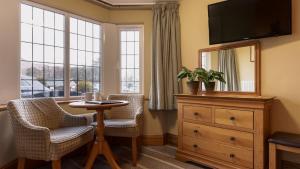a room with two chairs and a dresser and a mirror at The Mary Mount Hotel in Keswick