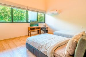 1 Schlafzimmer mit 2 Betten, einem Schreibtisch und Fenstern in der Unterkunft Luxury 3 Bedroom Condo - Infinity Pool - AWA Residences - Condo Anahuac 110 in Playa del Carmen