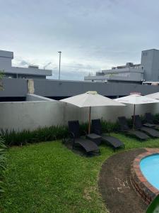 Un grupo de sillas y sombrillas junto a una piscina. en Pearl Holiday homes, en Vosburg
