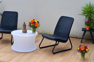 three chairs and a white table with flowers on it at Zen Garden House - in front of the metro in Pero