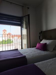 a bedroom with a bed with a purple pillow and a window at La Troje Pensión in Lucainena de las Torres
