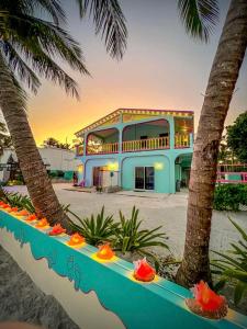 Un edificio azul con palmeras delante. en Barefoot Beach Belize, en Caye Caulker