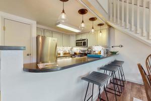 a kitchen with a counter with stools and a refrigerator at Snowmas Village A4 in Snowmass Village