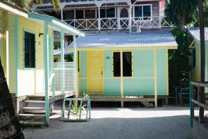 a small yellow and blue house with a porch at Barefoot Beach Belize in Caye Caulker