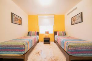 Dos camas en una habitación con paredes amarillas. en Ocean View Condo - 2 Bedrooms - at The Elements Condos - Castillo de Arena, en Playa del Carmen