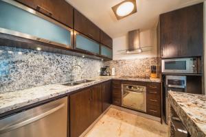 Una cocina con gabinetes de madera y encimeras de mármol. en Ocean View Condo - 2 Bedrooms - at The Elements Condos - Castillo de Arena, en Playa del Carmen 22 fotos más