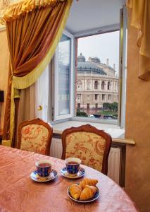 einen Tisch mit zwei Tassen und Croissants und einem Fenster in der Unterkunft Odessa Apartments Cherkasets in Odessa