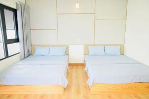 2 letti in una camera con pavimenti in legno di The Sunset a Phan Thiet