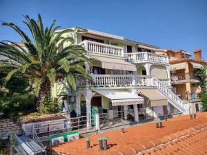 a large white house on the beach with a palm tree at Egidio Gigi Bellich holiday apartments family houses in Rabac