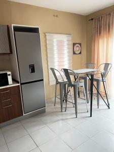 a kitchen with a table and chairs and a refrigerator at Cozy 2BR Bungalow Senegambia in Serekunda