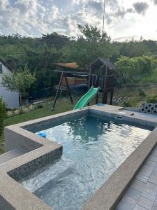 a swimming pool with a slide and a playground at Holiday home in Balatongyörök 43114 in Balatongyörök
