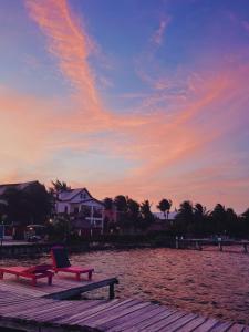 a chair sitting on a dock on the beach at sunset at Barefoot Beach Belize in Caye Caulker