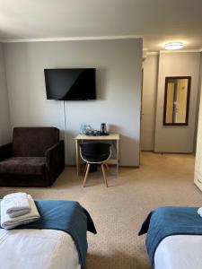 a hotel room with two beds and a desk with a tv at Villa FOREST in Poznań