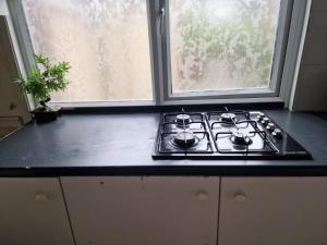 a stove top in a kitchen with a window at Cosy Beds & Rooms in London