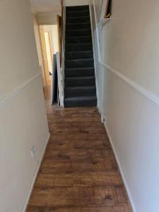a hallway with a staircase with a wooden floor at Cosy Beds & Rooms in London