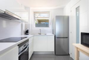 a kitchen with white cabinets and a stainless steel refrigerator at Los Gigantes,luxury aircon, views and pools in Puerto de Santiago
