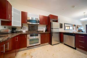a kitchen with wooden cabinets and stainless steel appliances at Condo Surf 301 - Luxury Oceanview Beachfront with Gym - At El Faro Condos in Playa del Carmen +17 photos