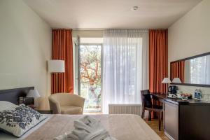 ein Schlafzimmer mit Bett, Schreibtisch und Fenster in der Unterkunft Baltic Inn in Palanga