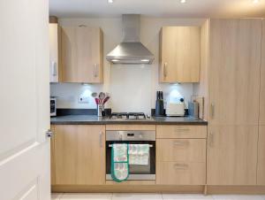 a kitchen with wooden cabinets and a stove top oven at Oysters in West Wittering