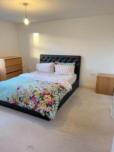 a bedroom with a bed with a floral quilt at Homely Stays Taunton in Norton Fitzwarren