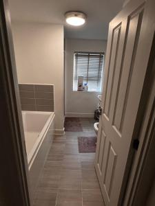 a bathroom with a tub and a toilet and a door at Homely Stays Taunton in Norton Fitzwarren +18 photos