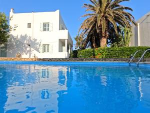 ein weißes Haus mit einer Palme und einem Swimmingpool in der Unterkunft Crisio Studios in Skyros