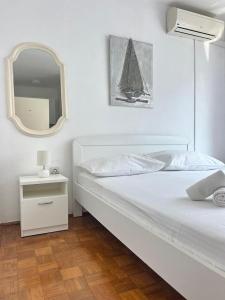 a white bedroom with a bed and a mirror at Villa Mare in Makarska