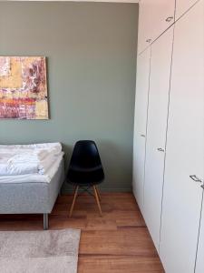 a bedroom with a bed and a black chair at Kolmio keskustasta in Ylivieska