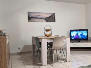 a dining room table with chairs and a television at La gemmeuse Meublé de tourisme 3 étoiles in Aureilhan