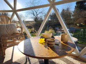 a wooden table in front of a large window at Dôme Saint-Eloi in Floursies +14 photos