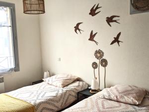 a bedroom with two beds and birds on the wall at La gemmeuse Meublé de tourisme 3 étoiles in Aureilhan