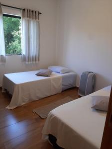 ein Schlafzimmer mit zwei Betten und einem Fenster in der Unterkunft Privacidade para sua família e grupos em um só lugar-2 quartos- melhor custo-benefício, garagem, sala com cozinha integrada, aconchegante, ambiente moderno e funcional, wi-fi veloz gratuito, próximo ao Parque das Águas-Calçadão e tudo que a cidade oferece in São Lourenço