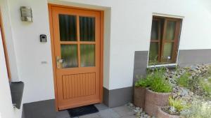 eine orangefarbene Tür an einem weißen Haus mit Pflanzen in der Unterkunft Ferienwohnung Jung in Hohenburg