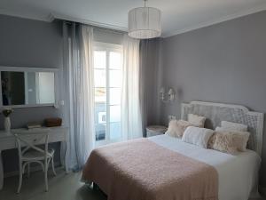 a bedroom with a bed and a desk and a window at Rincón del Mar Terrazas y vistas a la Ría de Vigo in Moaña