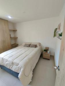 un grand lit dans une chambre blanche avec dans l'établissement Casa de la Sierra, à Santa Marta