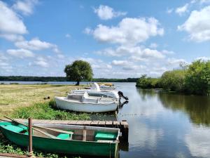 two boats are docked at a dock on a river at La gemmeuse Meublé de tourisme 3 étoiles in Aureilhan
