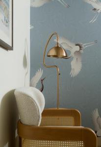 a lamp and a chair with white birds on the wall at The Milo in Santa Barbara
