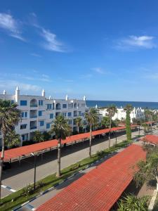 Una vista de un edificio con palmeras y una calle. en Penthous avec vue sur la mer, en Marina Smir
