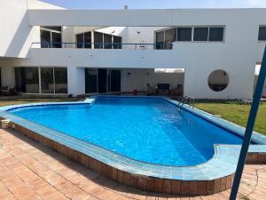 a large swimming pool in front of a house at مجمع ديار بالساحل الشمالي in Sidi Kirayr